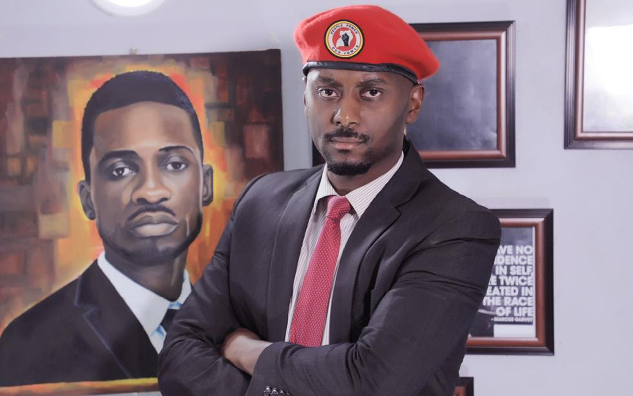 In the background is a portrait of Bobi Wine as painted by an artist. On the foreground is David Lewis Rubongoya. Courtesy Photo