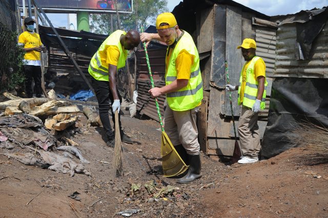The MTN CEO, Wim Vanhelleputte (2R) participates in a cleaning exercise at the Kiira Road police barracks during the 21 Days of y'ello care launch